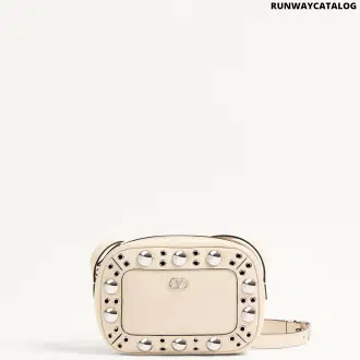 A Valentino Garavani Nellcôte chain shoulder bag in grainy calfskin leather, adorned with ball studs and rivets. Features a VLogo Signature metallic accent, palladium-finish hardware, zipper closure, and an adjustable leather strap for shoulder or cross-body wear. The suede-lined interior includes a card pocket for storage.