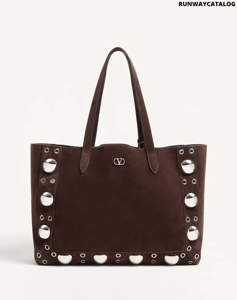 A Valentino Garavani Nellcôte suede shopping bag, crafted in soft suede with ball studs, rivets, and palladium-finish hardware. Features a removable inner pouch and double handles for versatile carrying options.