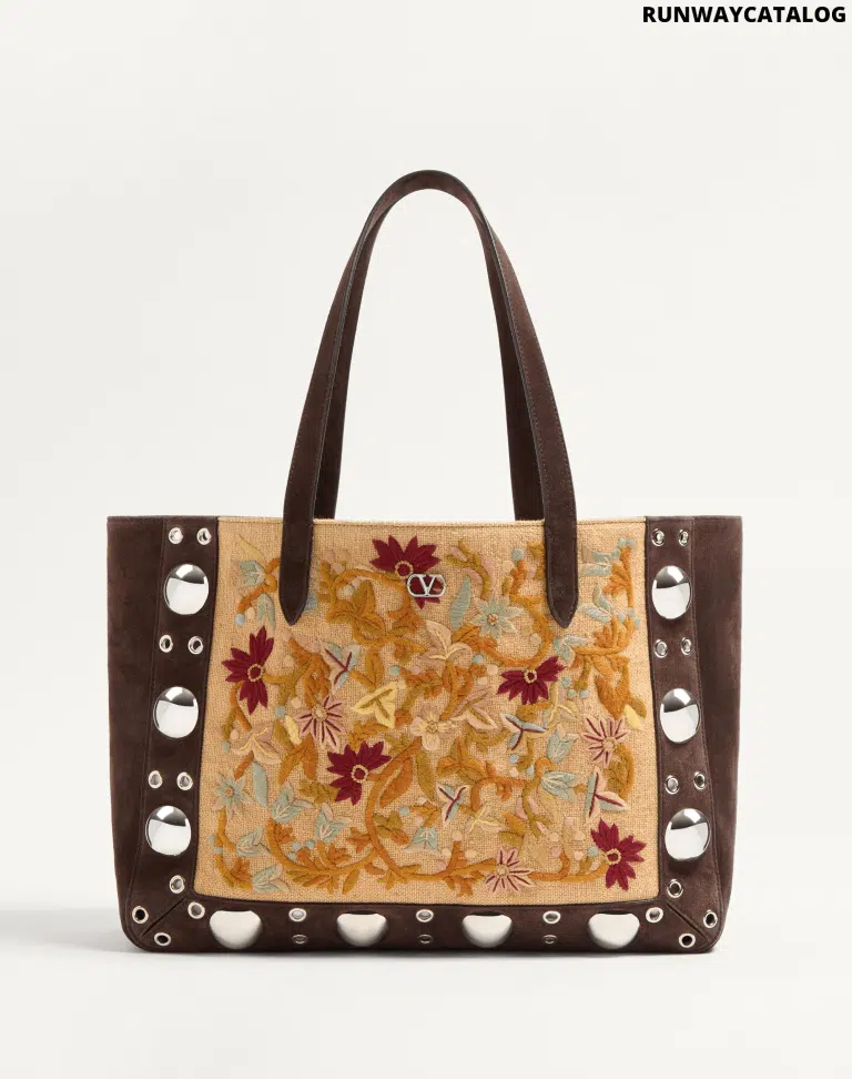 A Valentino Garavani Nellcôte shopping bag with intricate floral embroidery, studded detailing, and palladium-finish hardware. Includes a removable inner pouch and double handles for effortless carrying.