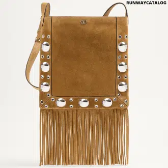 A Valentino Garavani Nellcôte suede shoulder bag with long fringe details, studded trim, and an adjustable suede strap for crossbody or shoulder wear. Features palladium-finish hardware and a VLogo metallic accent.